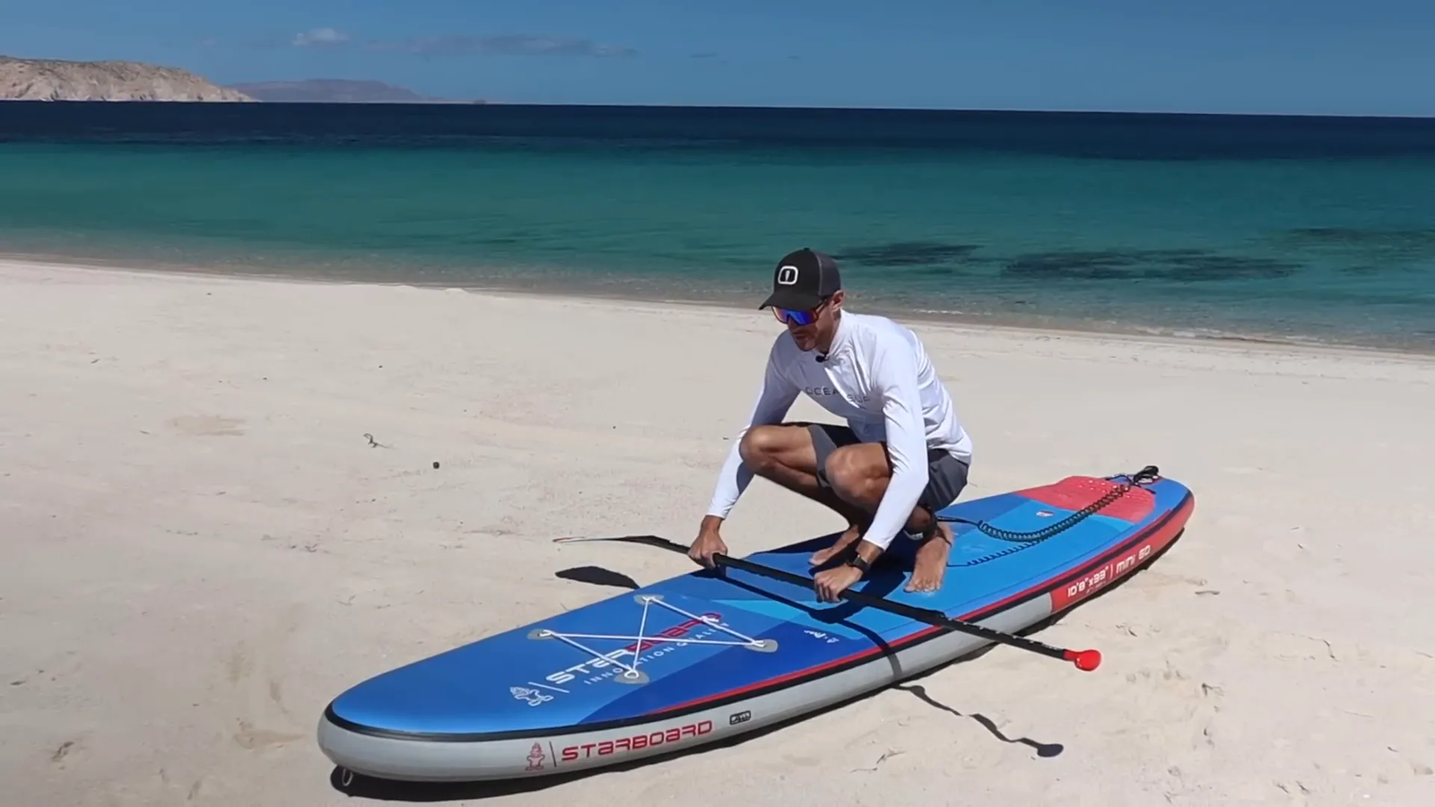 Beginner standing up on paddle board with paddle in water